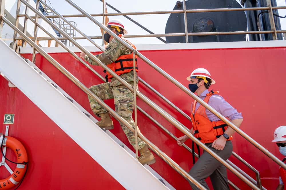 Senator Ossoff in a life vest and hard hat climbing the stairs on a container ship in the Port of Savannah.